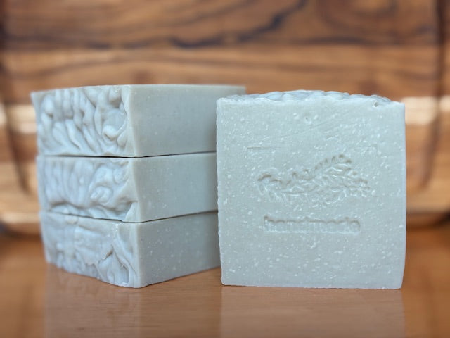 Three blocks of light green soap with a textured surface on a wooden background
